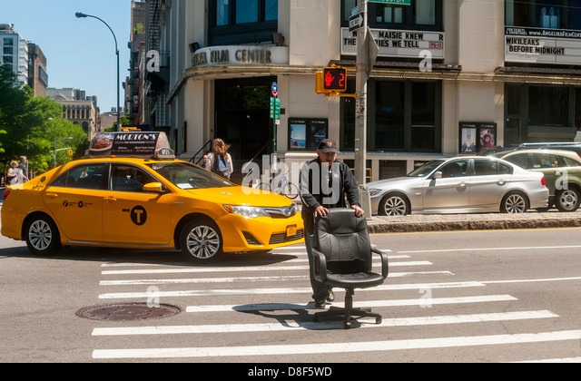 new-york-ny-older-man-pushing-an-office-chair-across-houston-street-d8f5wd.jpg